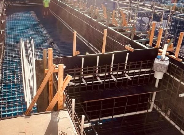 Steel reinforcement and service penetrations in a rooftop pool shell before concreting